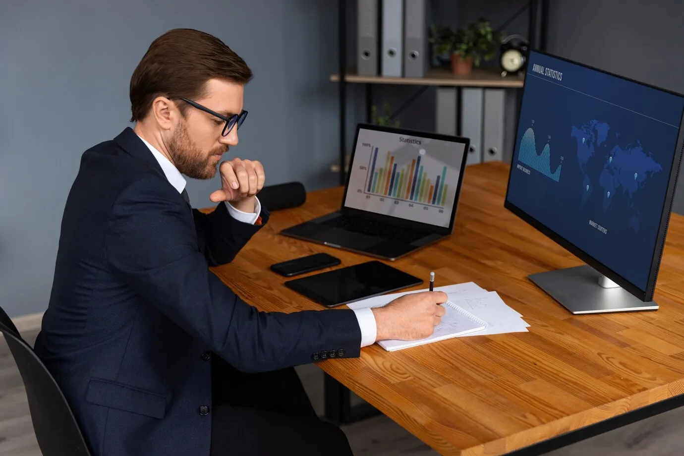 Professional auditor analyzing financial statistics and annual data on dual monitor setup in modern office