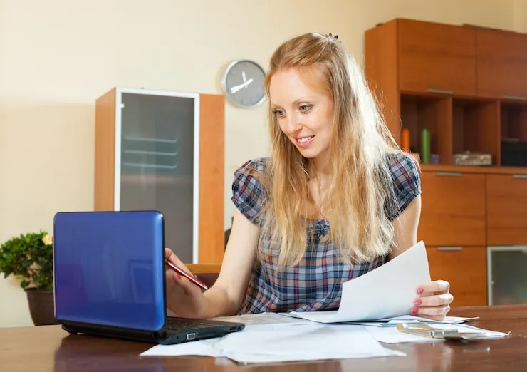 Female business owner managing tax documents and financial records using laptop.