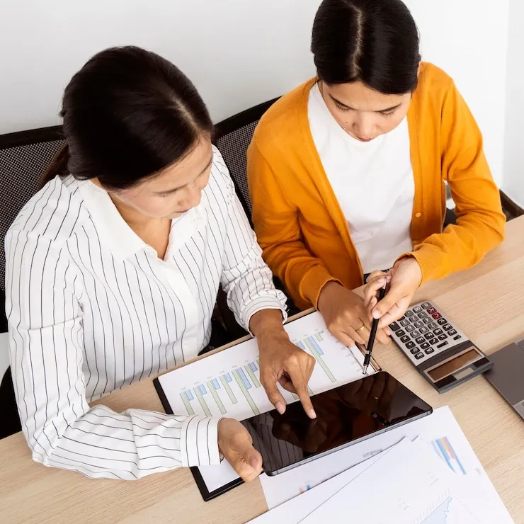 Two professional cryptocurrency tax specialists reviewing digital asset transactions and tax calculations on tablet