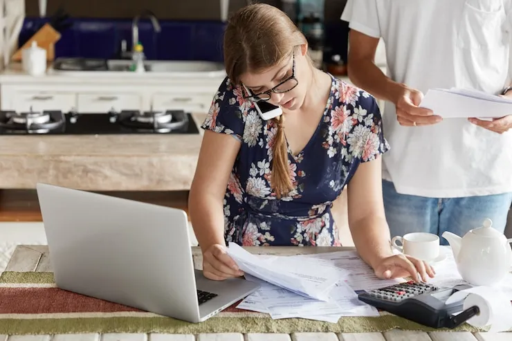 Female corporate accountant working on financial documents and tax calculations with laptop and calculator