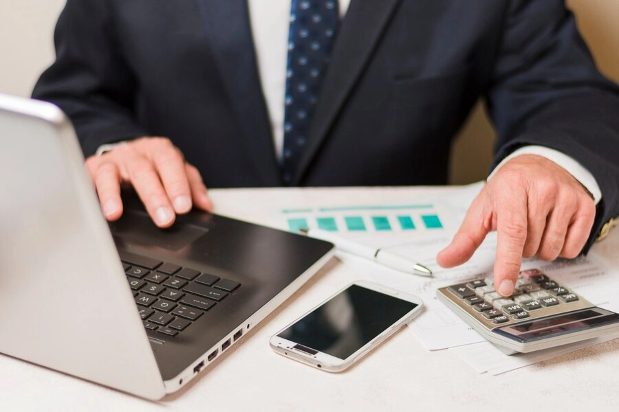 professional reviewing financial data with calculator and laptop