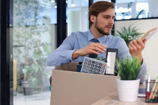 Pearl Lemon Accountants – Man packing office supplies, including a calculator and notebook, preparing for workspace reorganization.