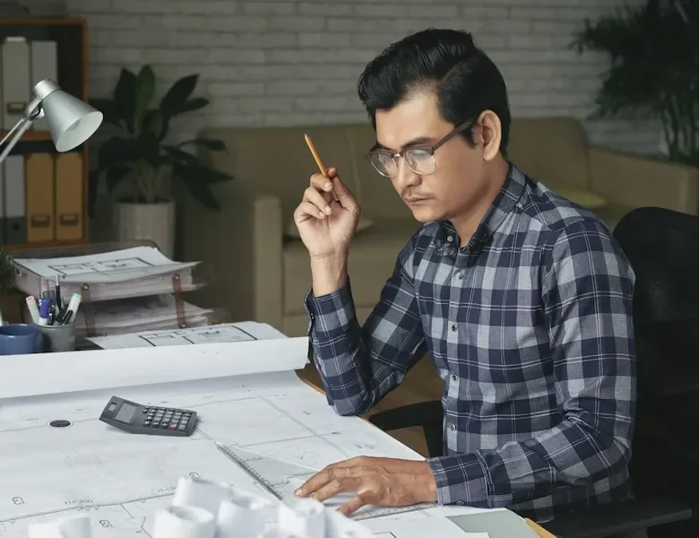Professional architect reviewing architectural plans and financial documents for specialized accounting services