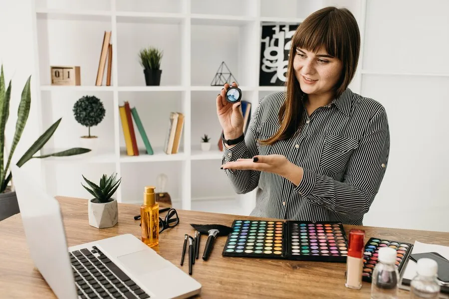Female artist managing finances with makeup palette and laptop for creative professionals accounting services