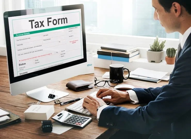 Professional accountant completing UK tax forms and HMRC compliance documentation on computer